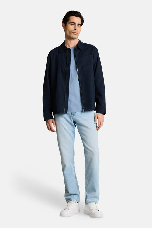 T-shirt bleu à manches courtes de Tom Tailor, porté avec une veste bleu marine zippée et un jean délavé.