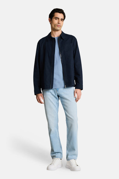 T-shirt bleu à manches courtes de Tom Tailor, porté avec une veste bleu marine zippée et un jean délavé.