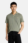 Tom Tailor poloshirt met wafelstructuur en V-hals, gedragen door een man met een zwarte jeans en witte sneakers.