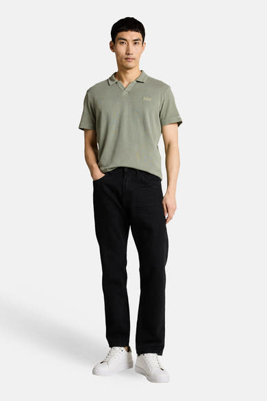 Polo kaki de Tom Tailor à col V gaufré, porté par un homme avec un jean noir et des baskets blanches.
