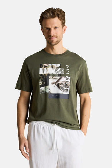 T-shirt vert à manches courtes de Tom Tailor avec motif graphique et texte vertical, porté avec un short blanc.