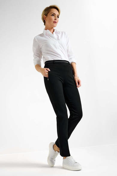 Pantalon noir de RAPHAELA, coupe droite, porté avec une chemise blanche et des baskets blanches.