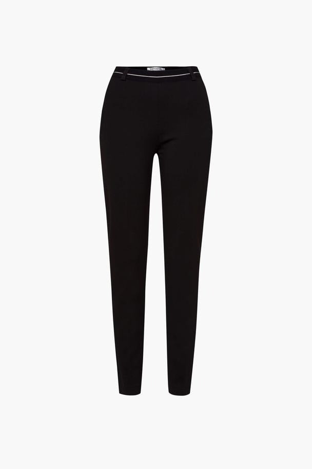Pantalon noir de RAPHAELA, coupe droite, avec une ceinture fine blanche.