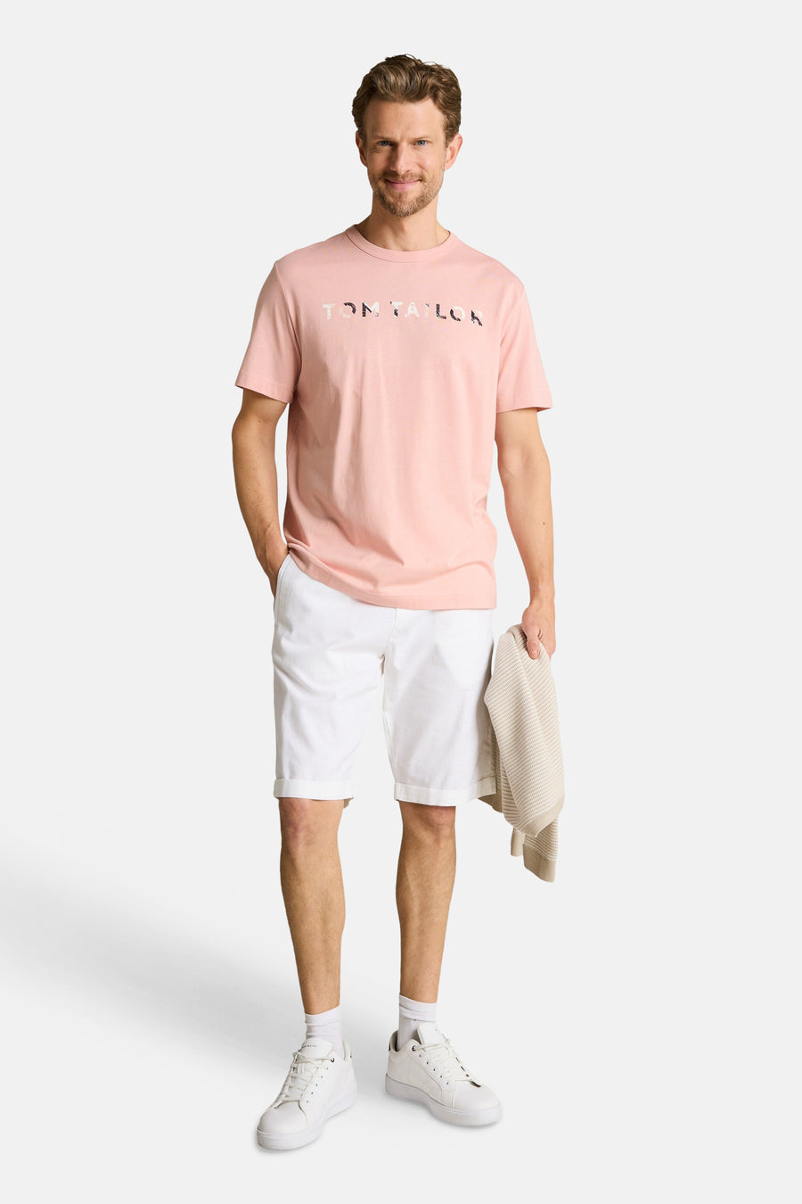T-shirt rose de Tom Tailor avec lettrage TOM TAILOR à motifs, porté par un homme en short blanc.
