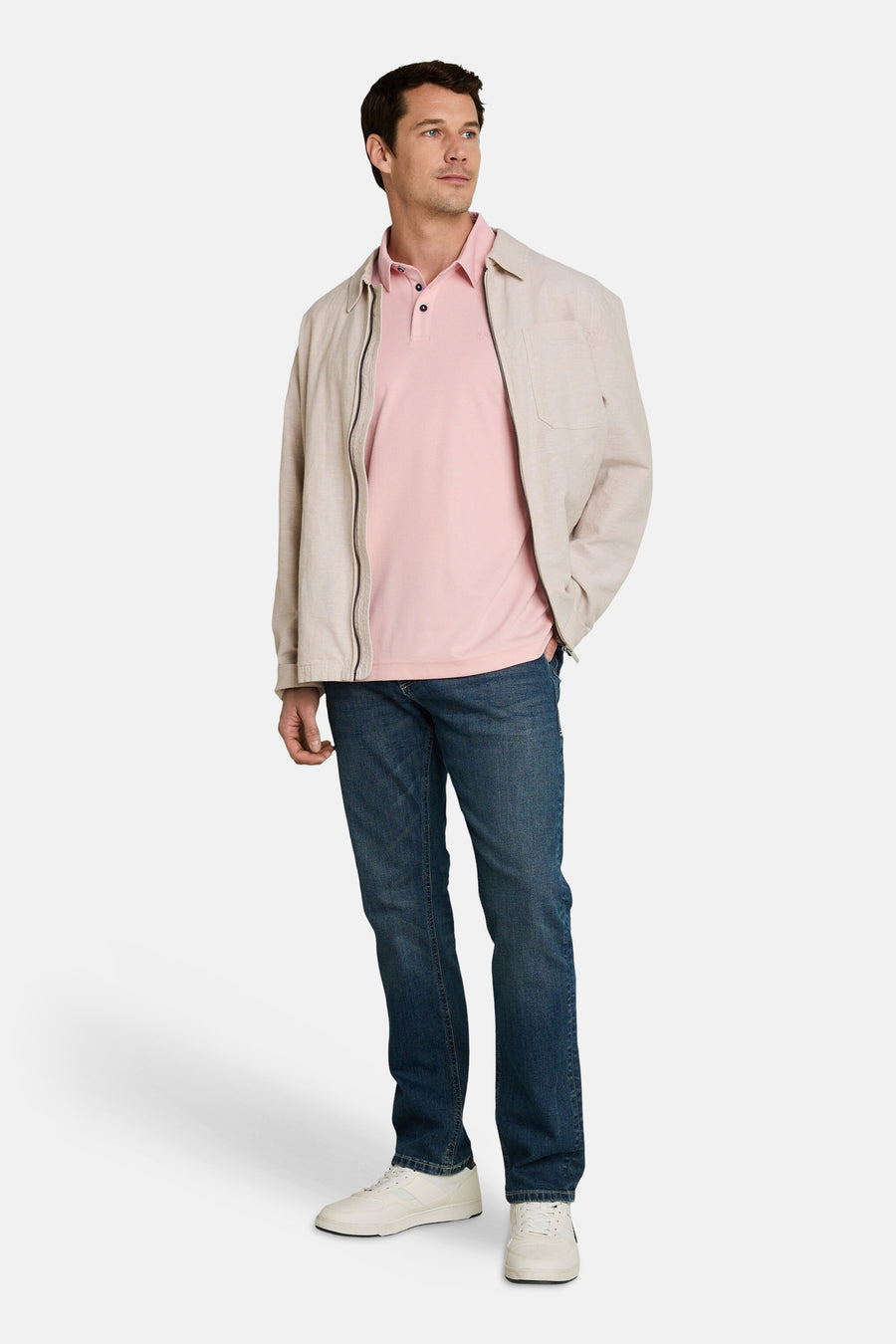 Polo rose de Tom Tailor avec col à trois boutons, porté sous une veste beige avec un jean bleu et des baskets blanches.