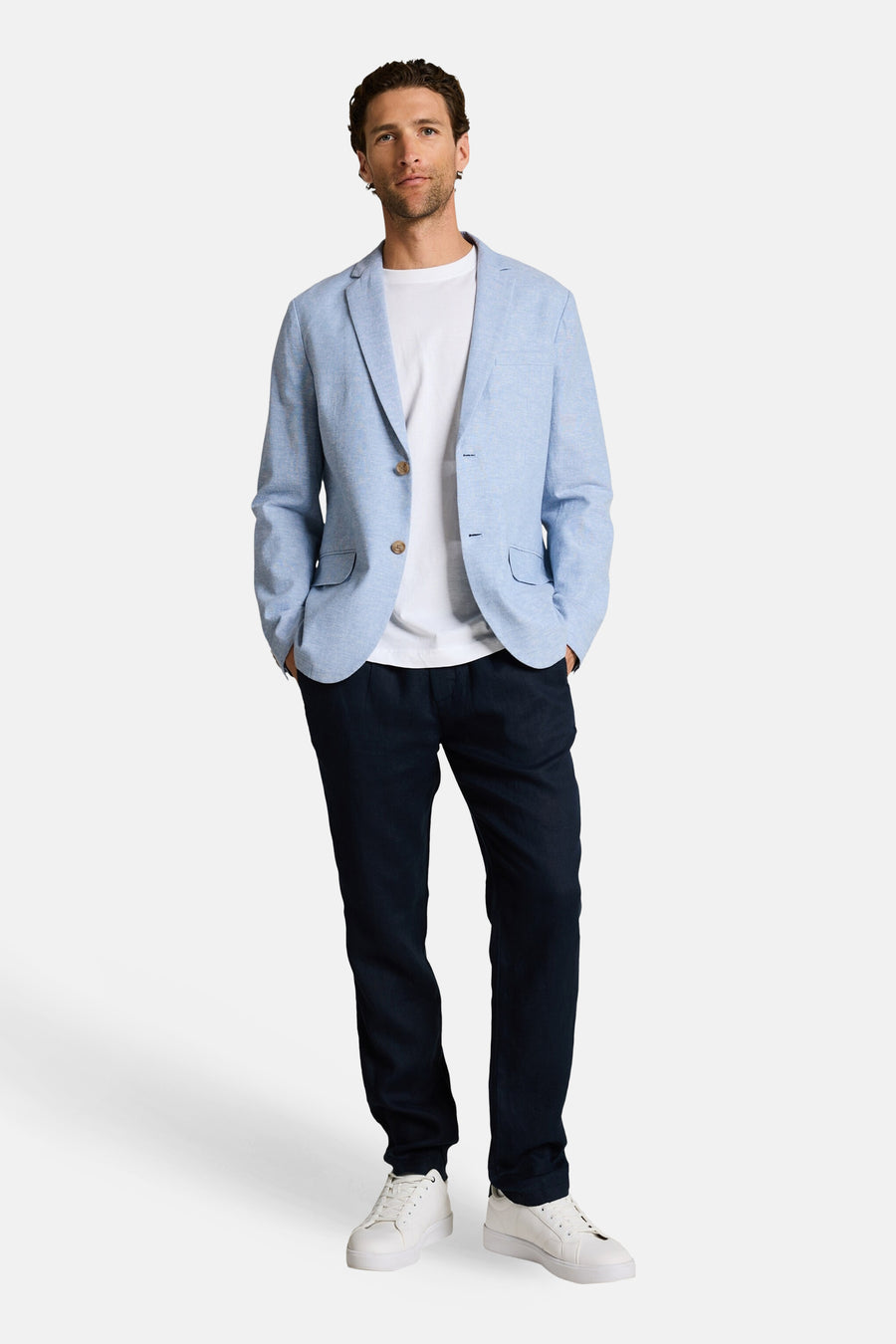 Blazer bleu de Tom Tailor en tissu texturé, porté ouvert sur un t-shirt blanc avec un pantalon foncé et des baskets.