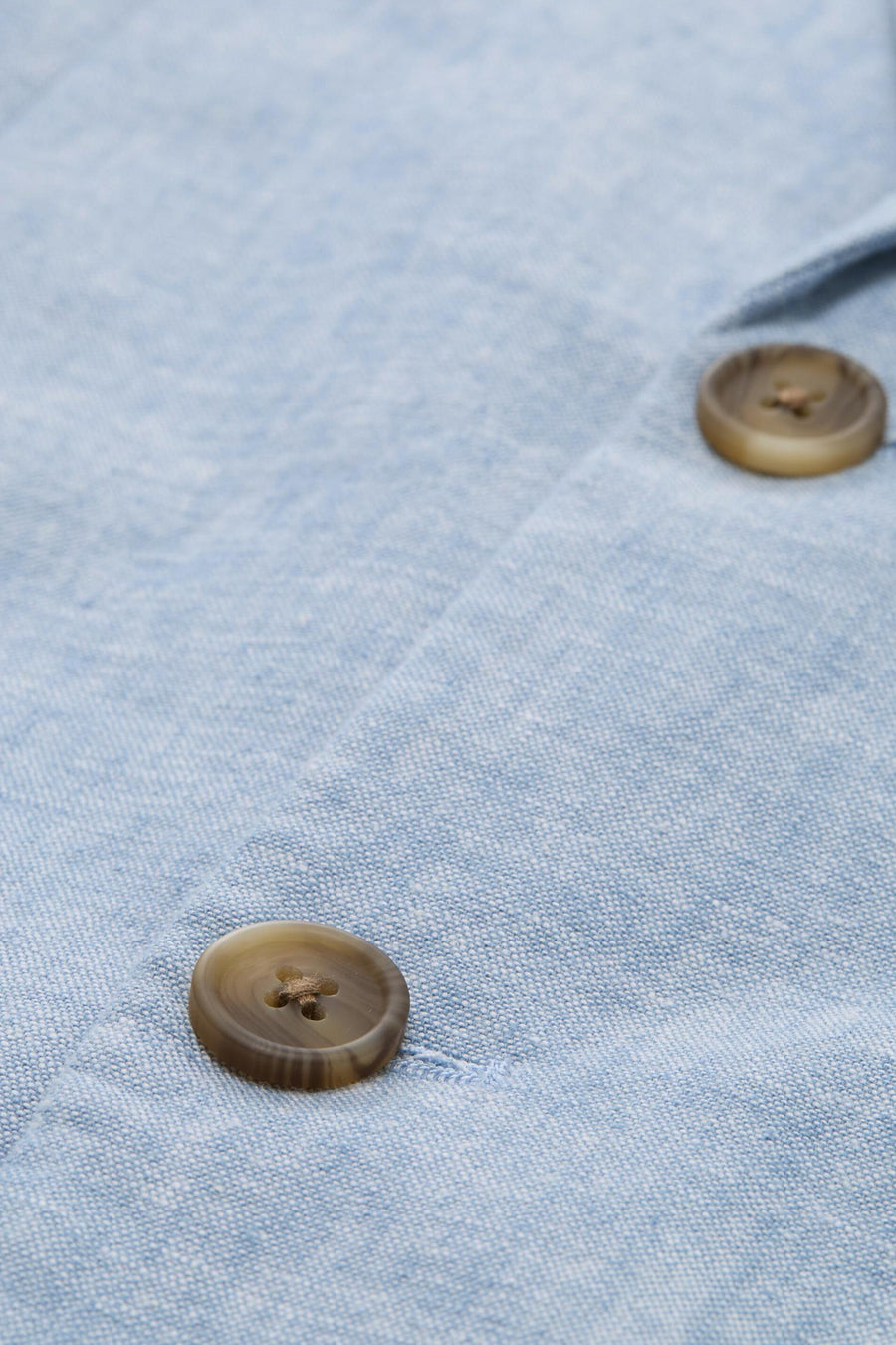 Blazer bleu clair de Tom Tailor avec une texture tissée et deux boutons marron, vue rapprochée.