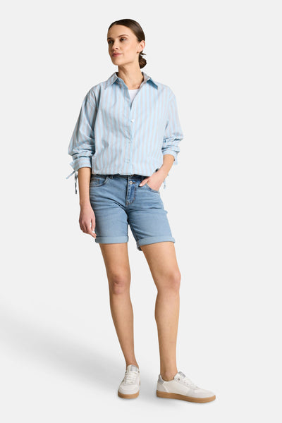 Bermuda en jean bleu clair de Tom Tailor, à revers, porté avec une chemise rayée et des baskets.