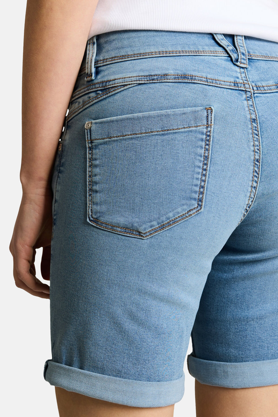 Bermuda en jean bleu clair de Tom Tailor, vue de dos, avec poche arrière et ourlets retroussés, porté avec un haut blanc.