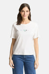 T-shirt blanc à manches courtes de Tom Tailor, orné de motifs cœurs délicats, porté avec un jean bleu.
