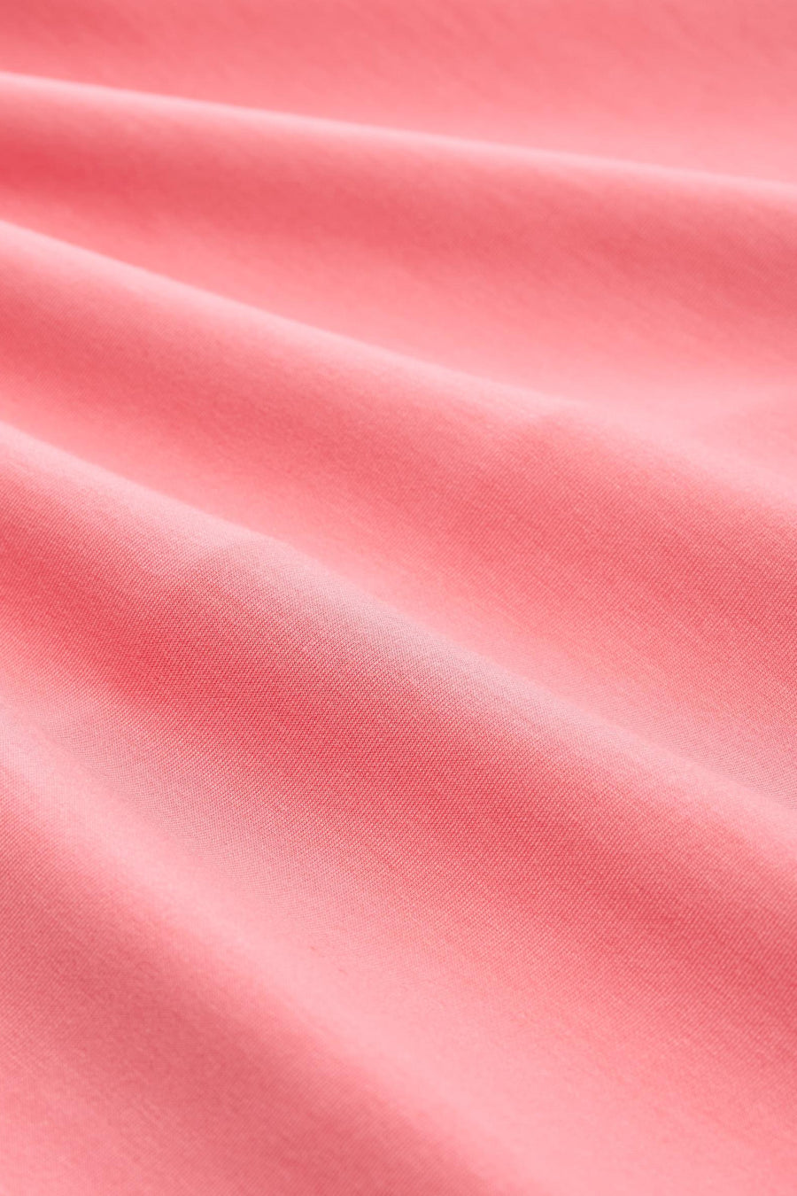 Polo corail de Tom Tailor en tissu texturé avec des plis doux, vue rapprochée.