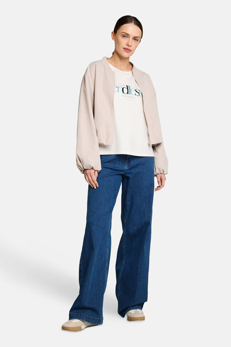 T-shirt blanc de Tom Tailor imprimé "endless summer", porté avec un blouson bomber beige, un jean large et des baskets.
