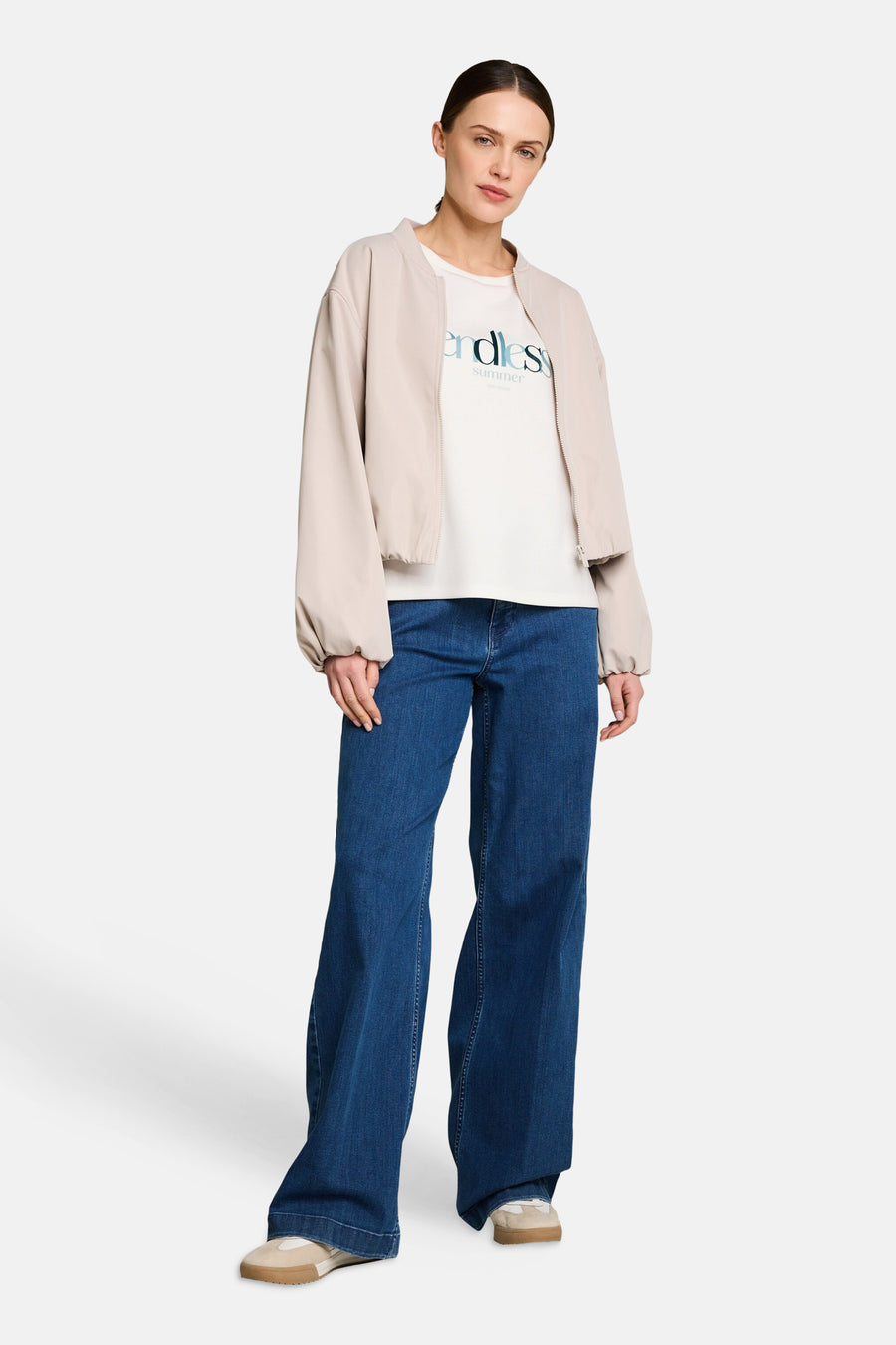 T-shirt blanc de Tom Tailor imprimé "endless summer", porté avec un blouson bomber beige, un jean large et des baskets.