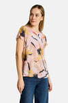 T-shirt à manches courtes multicolore de Tom Tailor, à motif abstrait, porté par une femme en jeans bleus, vue de côté.