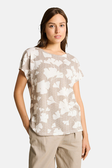 T-shirt beige à motif feuilles par Tom Tailor, porté avec un pantalon beige.