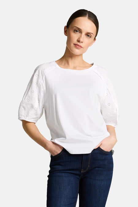 Top uni blanc à manches courtes de Tom Tailor avec broderies à œillets sur les manches, porté avec un jean.
