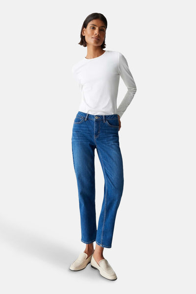 Jean skinny en denim bleu moyen d'OPUS, porté avec un haut blanc à manches longues et des chaussures plates crème.