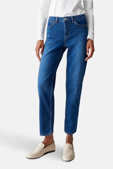 Jean skinny bleu denim by OPUS porté avec un haut blanc à manches longues et des mocassins beiges.
