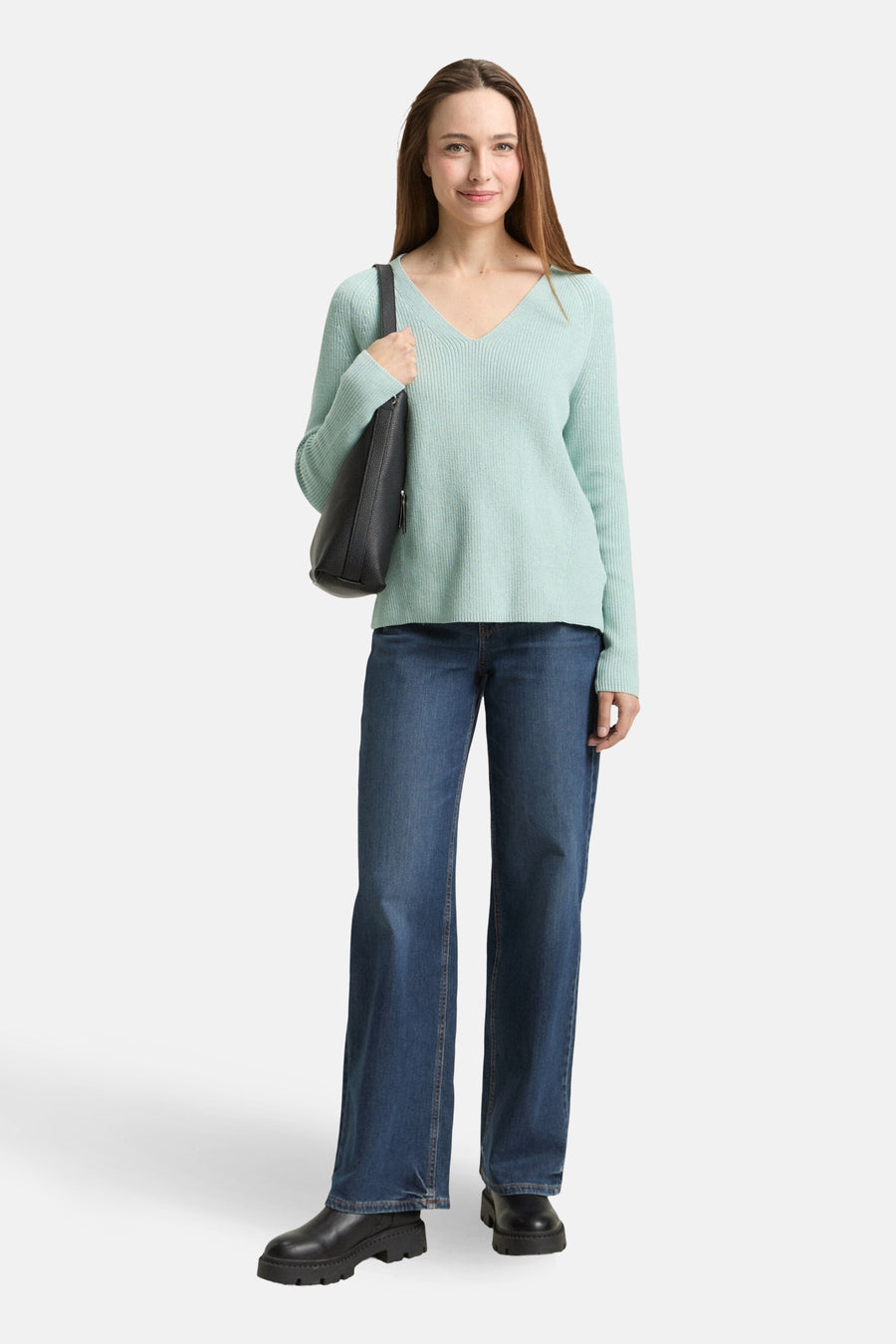 Pull à col en V vert de Tom Tailor, porté avec un jean bleu ample et un sac à main noir.