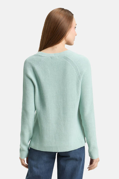 Pull col V vert de Tom Tailor, avec une texture côtelée et des manches longues, porté avec un jean bleu.
