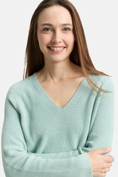 Groene V-hals trui van Tom Tailor, gedragen door een lachende vrouw met lang bruin haar.
