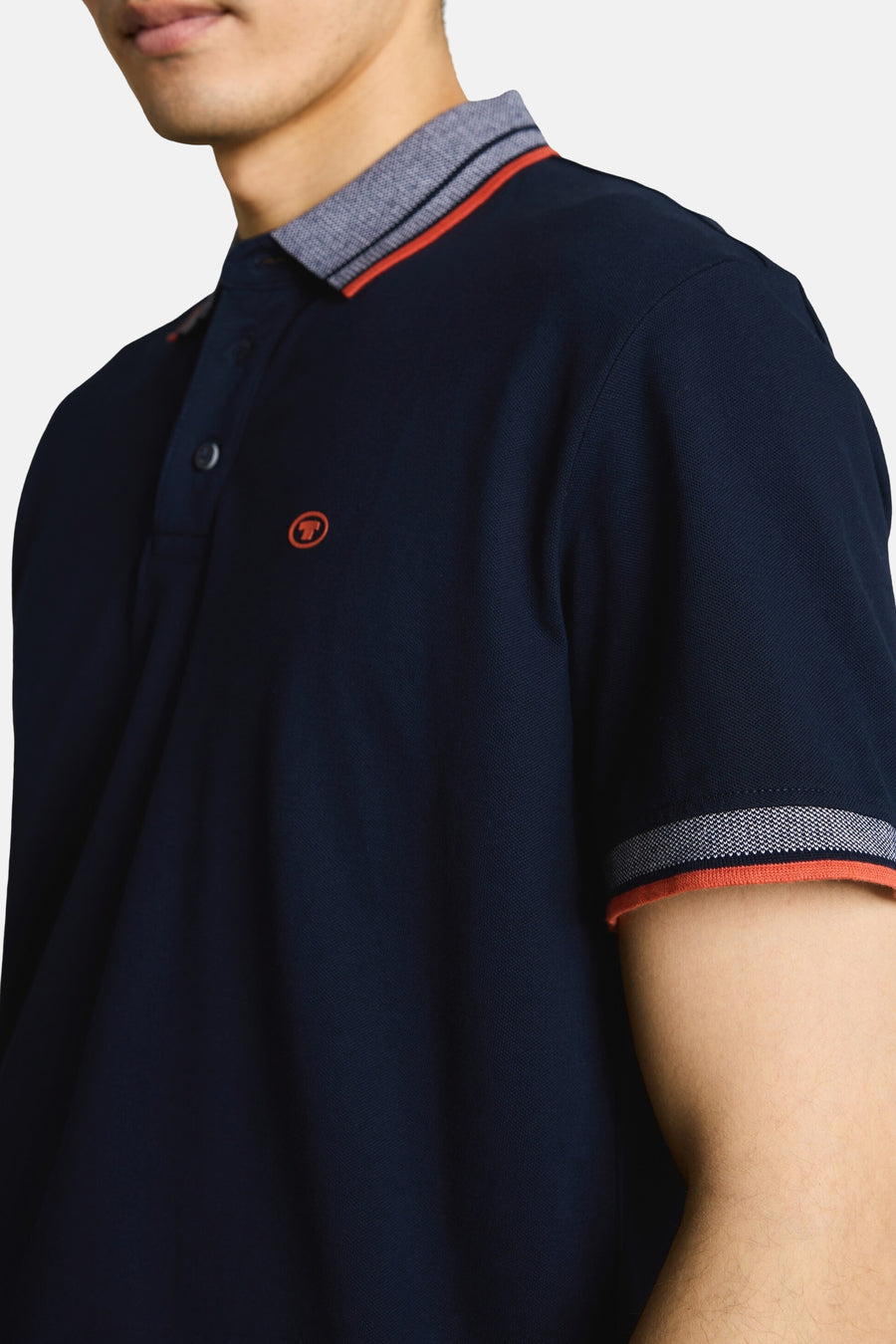 Donkerblauwe polo van Tom Tailor met geribde kraag en manchetten in grijs gemêleerd, oranje bies en 'T'-logo op de borst.