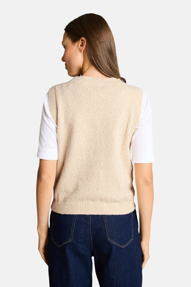 Beige mouwloze top van Tom Tailor, gedragen met een wit T-shirt met korte mouwen en een donkerblauwe jeans met hoge taille.