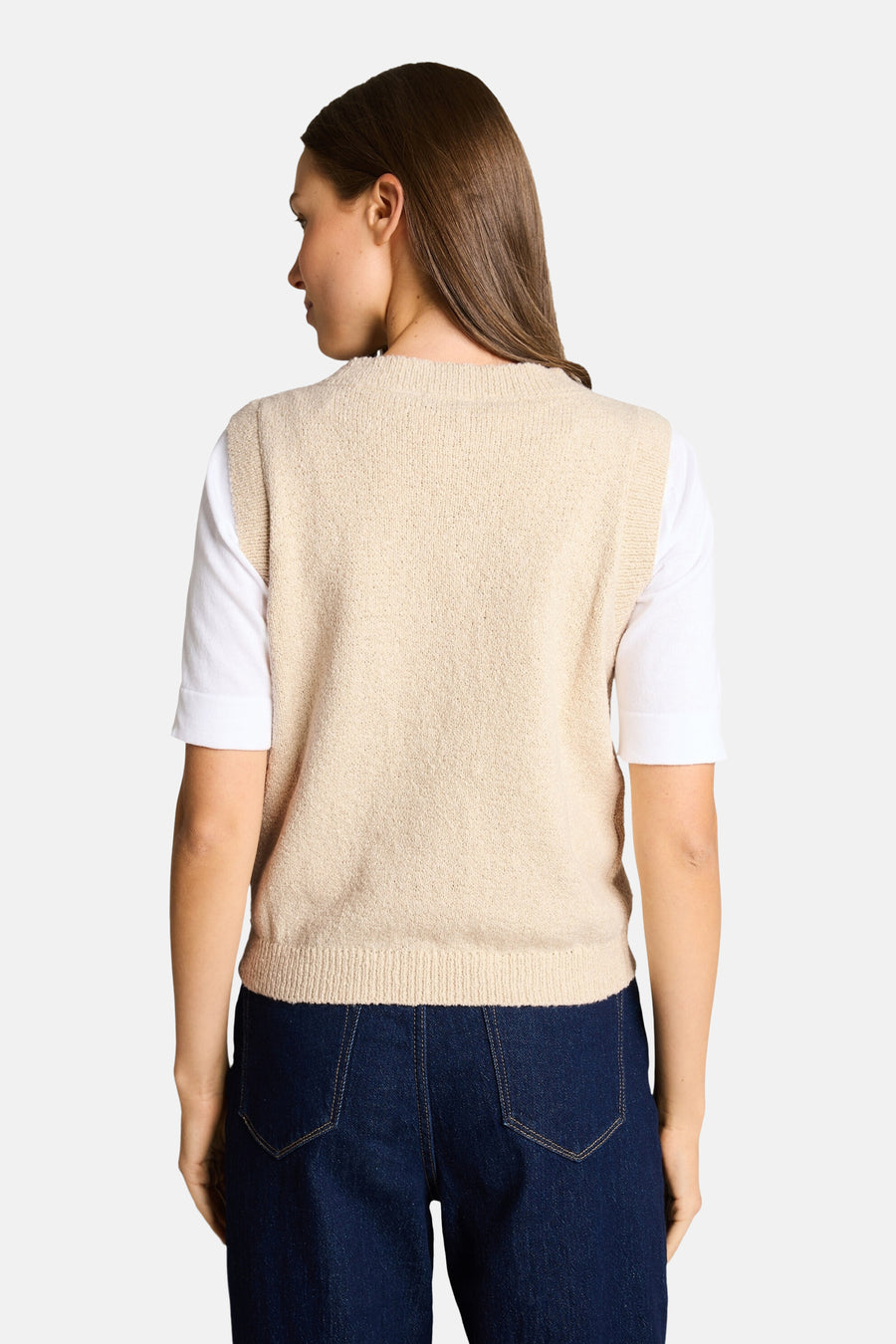 Beige mouwloze top van Tom Tailor, gedragen met een wit T-shirt met korte mouwen en een donkerblauwe jeans met hoge taille.
