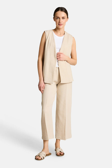 Beige broek van Tom Tailor in kreukelstof, met vouwen en zichtbare knoop, hand in de zak.
