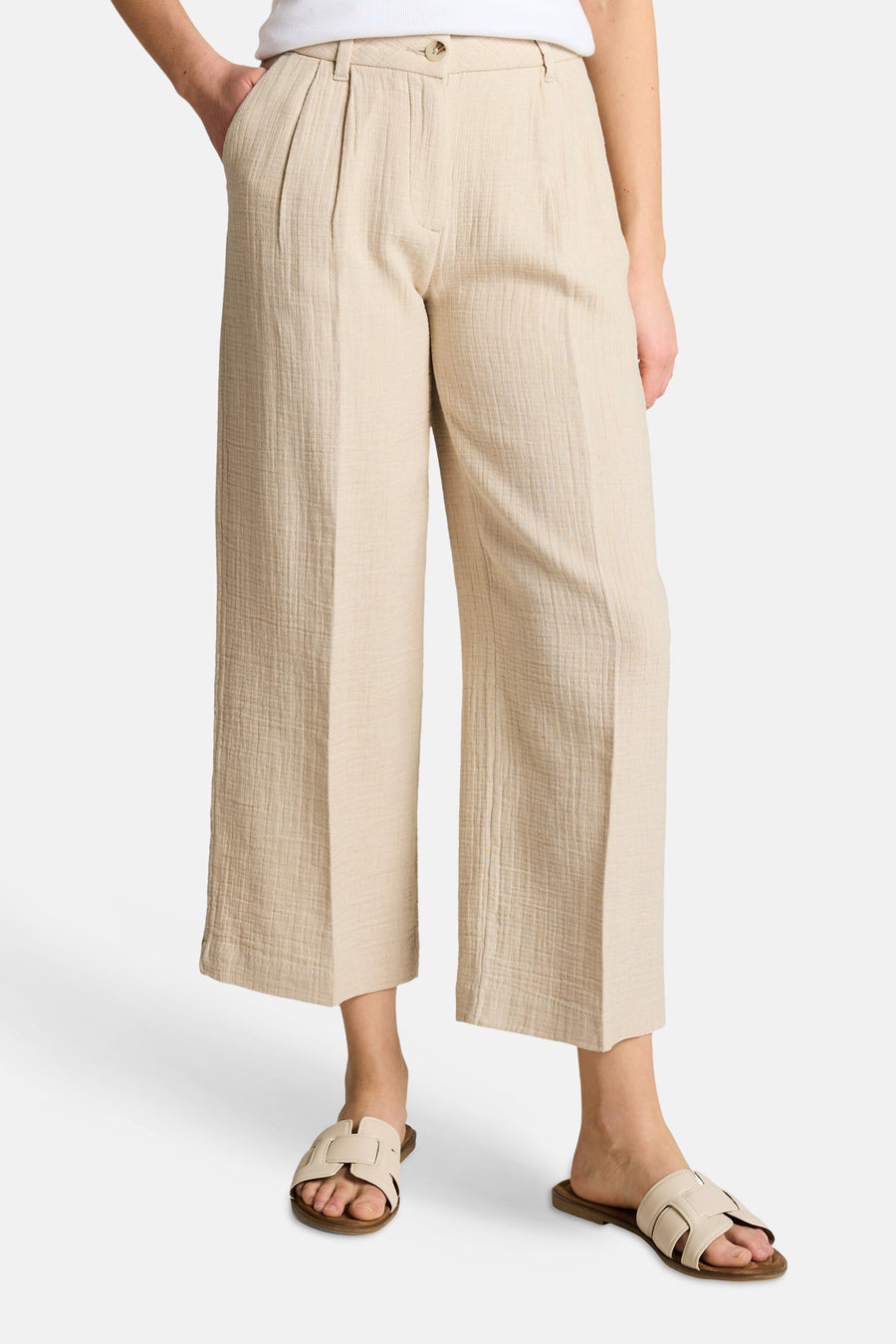 Beige broek van getextureerde stof van Tom Tailor, wijde pasvorm met plooien, gedragen met lichte sandalen.