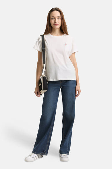 T-shirt blanc de Tom Tailor avec un petit motif sur la poitrine, porté avec un jean et des baskets.