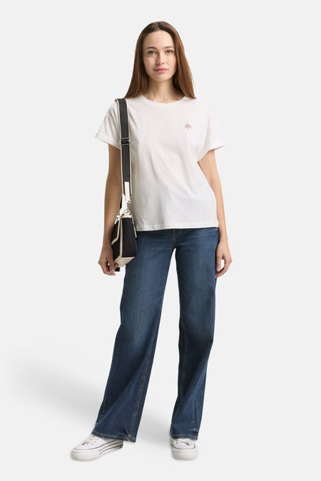 T-shirt blanc de Tom Tailor avec un petit motif sur la poitrine, porté avec un jean et des baskets.