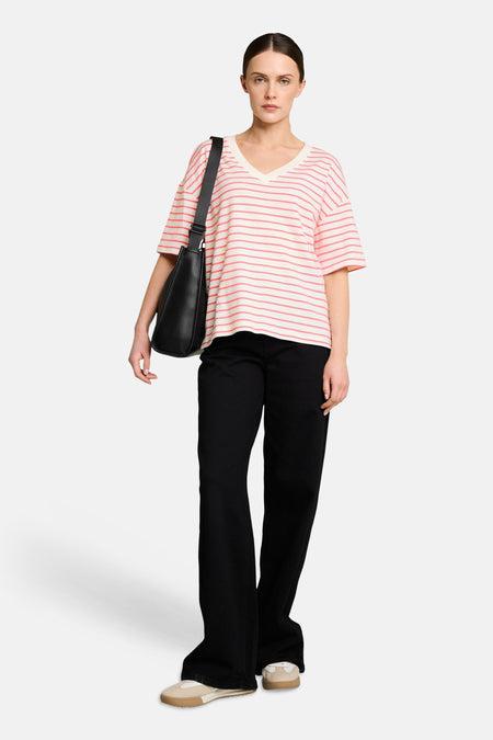 T-shirt multicolore à rayures, de Tom Tailor, porté avec un pantalon noir large et un sac à bandoulière.