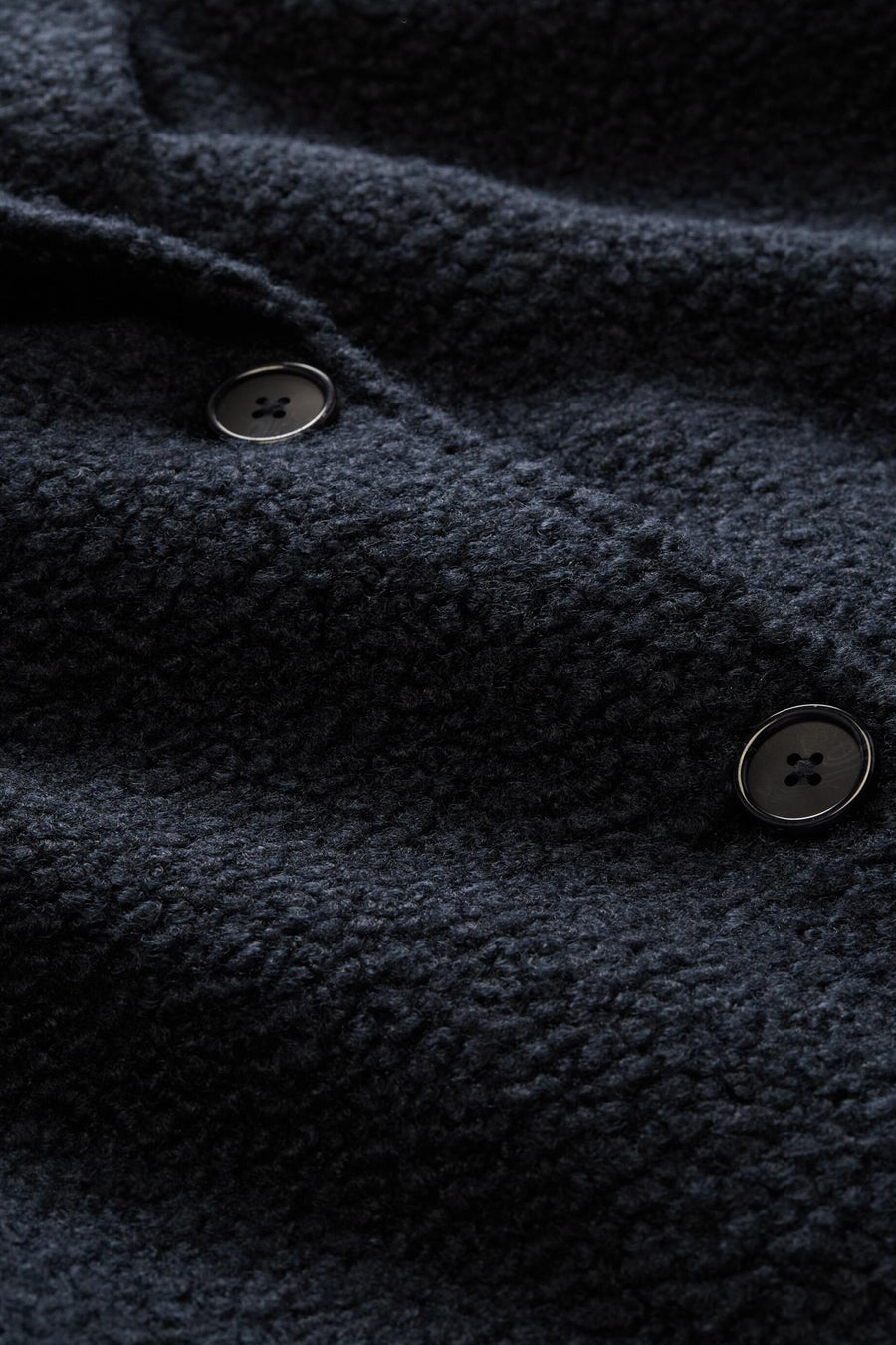 Blue textured poncho with dark buttons, close-up view showing fabric detail and stitching