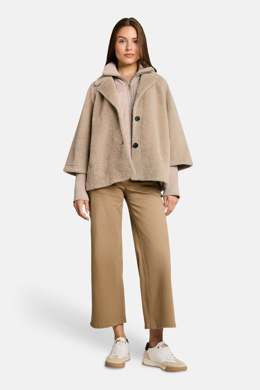 Taupe fuzzy poncho with wide sleeves and black buttons, worn over a quilted top and beige pants, full-length front view.