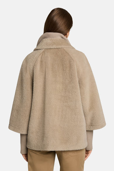 Taupe faux fur poncho with ribbed collar and cuffs, back view, worn over beige knit top and trousers