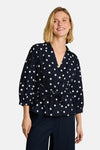 Navy polka dot short-sleeve blouse by Tom Tailor, featuring wrap front and tie waist, worn with matching trousers in lifestyle front view.