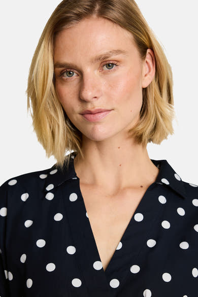 Navy blue short-sleeve blouse with white polka dots by Tom Tailor, featuring a V-neck and collar, shown in close-up front view.