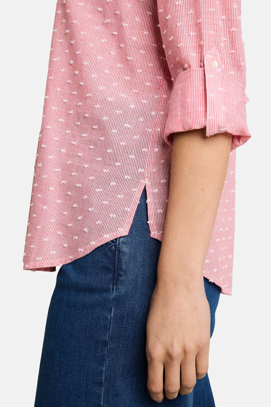Pink long-sleeve blouse with white dotted pattern by Tom Tailor, rolled cuffs, worn with blue jeans, side view