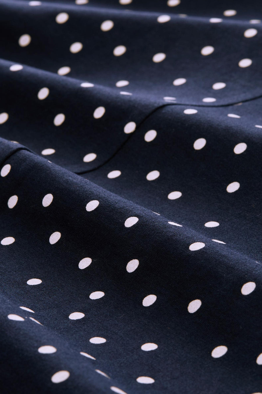 Multicolored 3/4-sleeve blouse with navy blue fabric and white polka dot pattern, close-up texture view