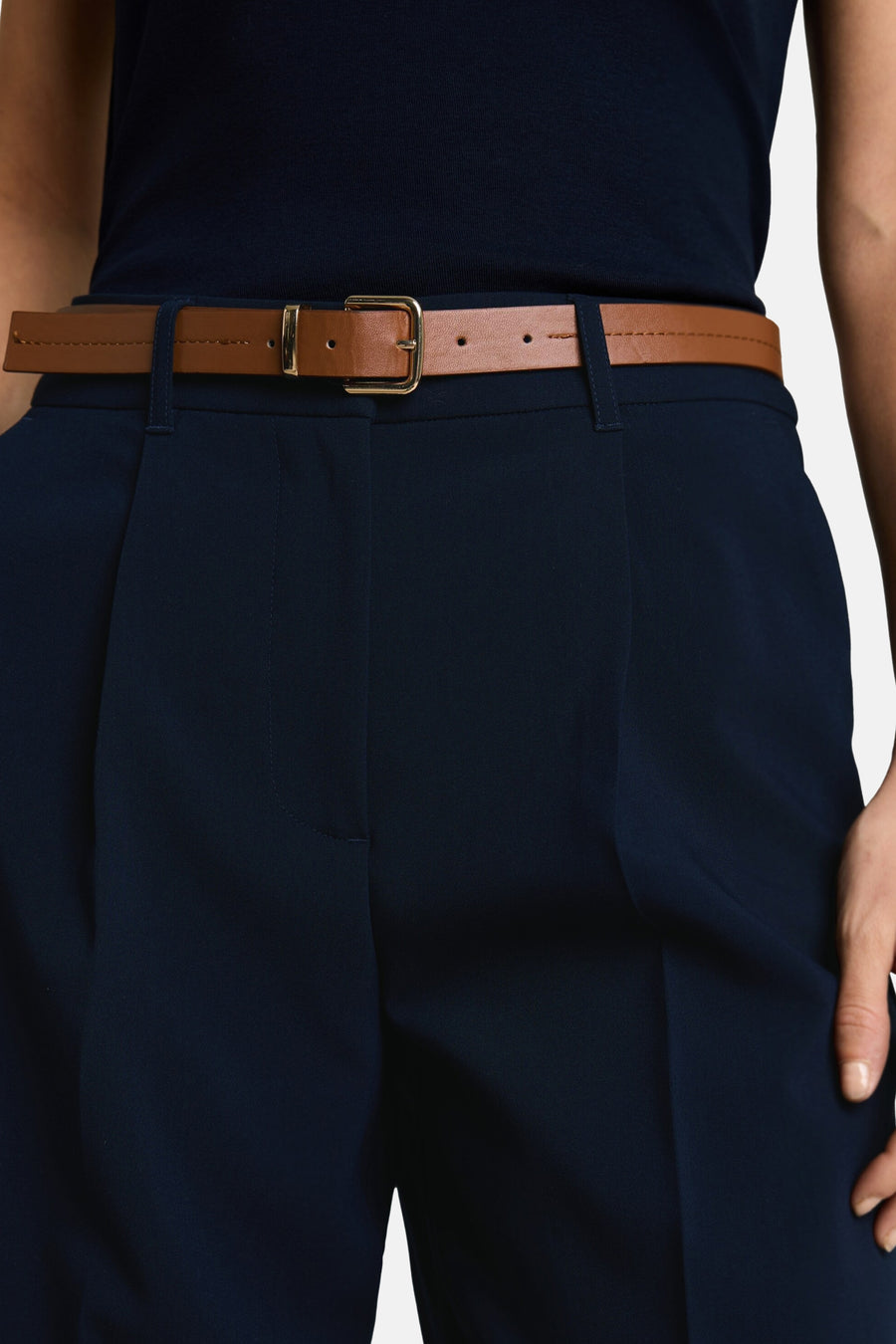 Navy blue suit trousers by Tom Tailor, featuring front pleats and a brown leather belt with gold buckle, worn with a dark top in a cropped lifestyle view.