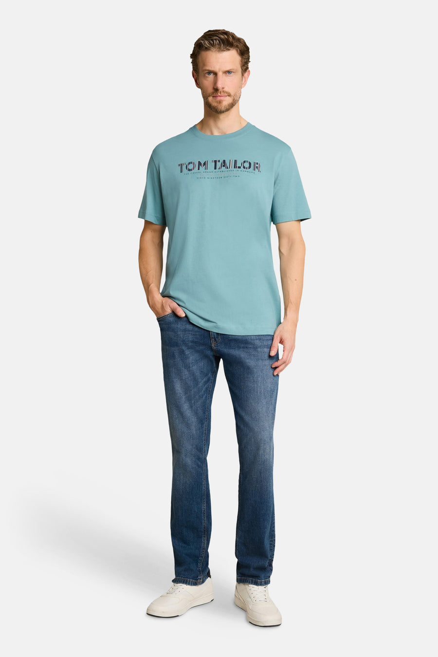 Blue short-sleeve T-shirt by Tom Tailor with front logo print, worn with jeans and white sneakers, full-length front view