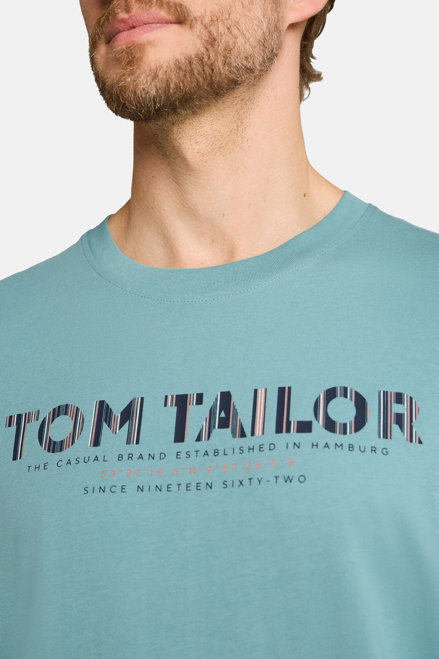 Teal short-sleeve T-shirt by Tom Tailor with bold striped logo print and text details, shown in close-up front view