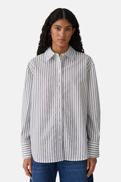 Chemise rayée à manches longues blanche, de OPUS, portée par une femme avec un jean.