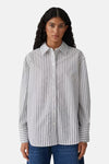 Chemise rayée à manches longues blanche, de OPUS, portée par une femme avec un jean.