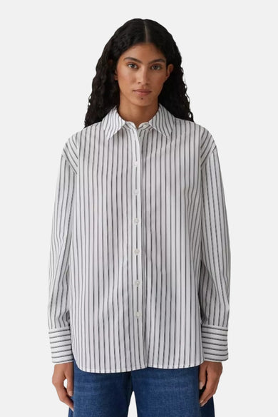 Chemise rayée à manches longues blanche, de OPUS, portée par une femme avec un jean.