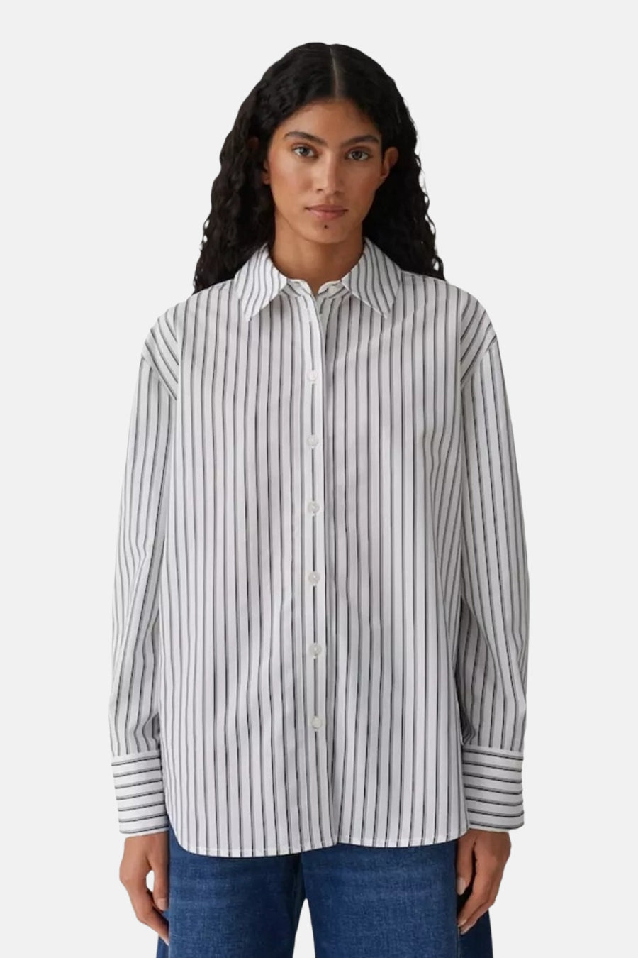 Chemise rayée à manches longues blanche, de OPUS, portée par une femme avec un jean.