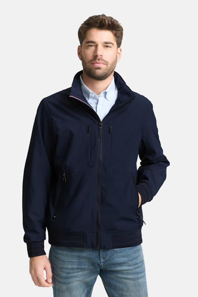 Korte blauwe jas van Tom Tailor, gedragen met een gestreept overhemd en een spijkerbroek, witte schoenen.