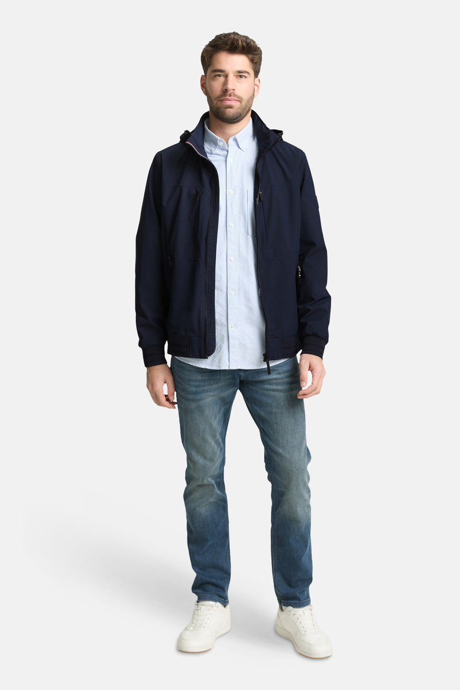 Veste courte bleue de Tom Tailor, portée avec une chemise rayée et un jean, chaussures blanches.