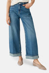 Jean large en denim bleu moyen par OPUS, avec ourlets retournés et chaussures plates taupe.

